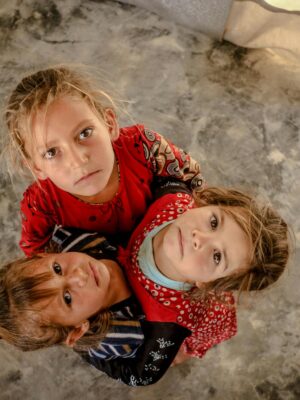 Three children in Idlib, Syria look up, showcasing innocence and unity.